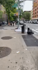 Person sleeps on sidewalk mattress in NYC street scene