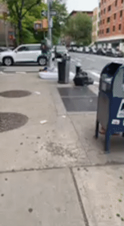 Person sleeps on sidewalk mattress in NYC street scene