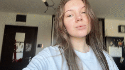 Woman adjusts hair playfully in Belgrade apartment Sunday morning