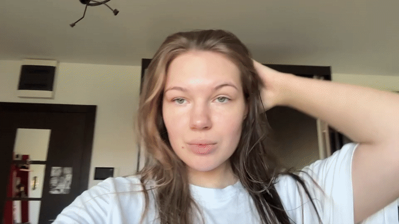 Woman adjusts hair playfully in Belgrade apartment Sunday morning