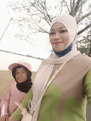 Woman in hijab walks with child, takes selfie