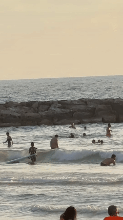 Tel Aviv beach crowd gathers under a golden sunset