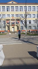 Woman crosses street near public building in Chaikovsky