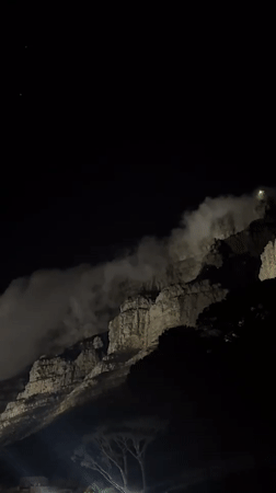 Table Mountain illuminated at night with flowing clouds captured