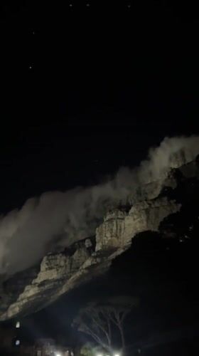 Table Mountain illuminated at night with flowing clouds captured