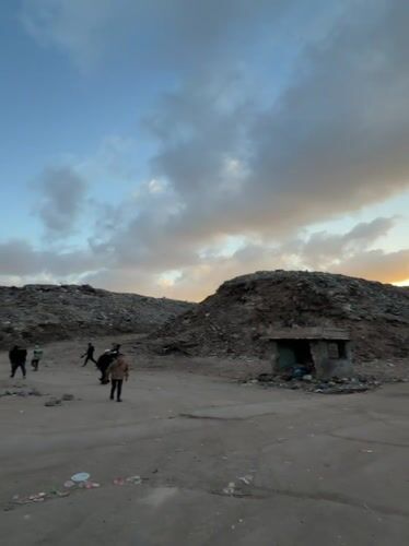 People navigate trash heaps in Gaza during afternoon hours