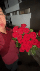 Young man holds red roses bouquet in nighttime Zlatograd scene