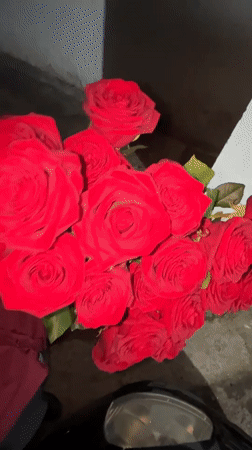 Young man holds red roses bouquet in nighttime Zlatograd scene