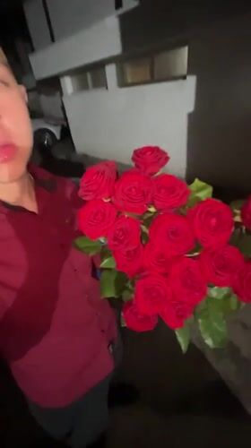 Young man holds red roses bouquet in nighttime Zlatograd scene