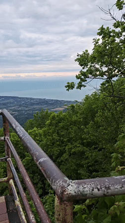 Tourist photographs coastal views from rusted observation platform in Abkhazia