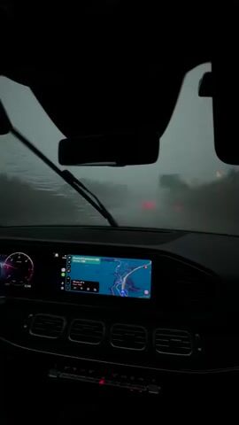 The video shows the interior of a car driving on a road in rainy conditions. The windshield is wet, obscuring the view outside. The car's dashboard is visible, with a navigation screen displaying a map. The time stamp shows the video beginning at 00:00 and ending at 00:04. The overall atmosphere is dark and moody, consistent with a heavy rainstorm.