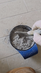 Person mixes gray substance in container on Tel Aviv floor