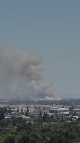 Heavy smoke plume rises over Sacramento skyline in clear conditions