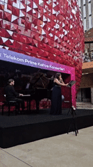 Piano and flute duo performs against geometric red backdrop