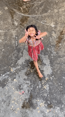Kids play in the rain across a flooded Dhaka rooftop