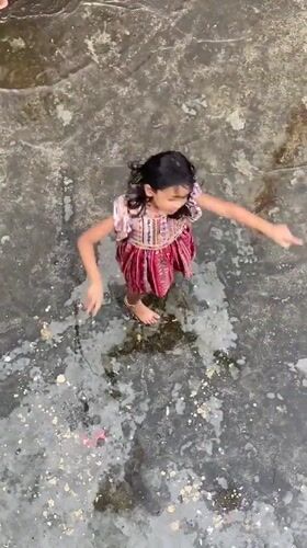 Kids play in the rain across a flooded Dhaka rooftop