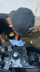 Man washes scooter in Madiun residential alley