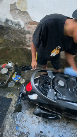 Man washes scooter in Madiun residential alley