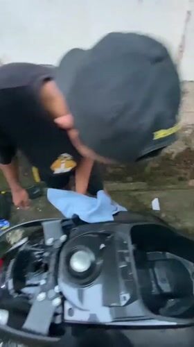 Man washes scooter in Madiun residential alley