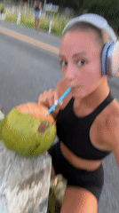 Woman takes coconut break during workout in Chalong