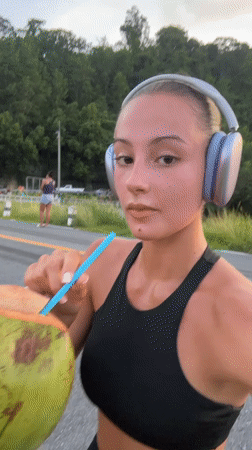 Woman takes coconut break during workout in Chalong