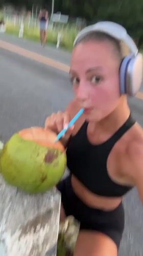 Woman takes coconut break during workout in Chalong