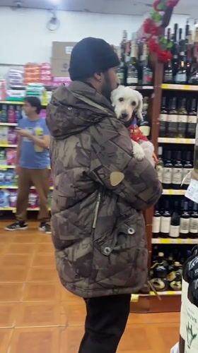 Man carries small dog through store in Wilde, Argentina