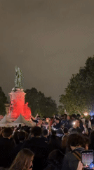 Crowd gathers at illuminated Place de la République statue
