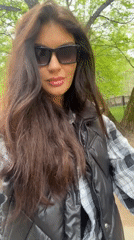 Woman adjusts sunglasses on tree-lined path in Krasnogorsk