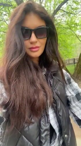Woman adjusts sunglasses on tree-lined path in Krasnogorsk