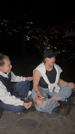Two women meditate overlooking Kyustendil city lights at night