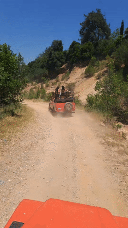 Jeeps traverse dirt road through wooded area near Kuşadası