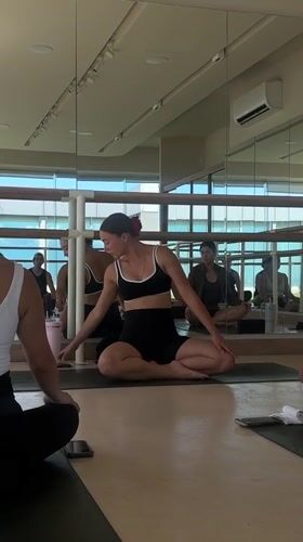 Settling into position on a yoga mat in a mirrored studio
