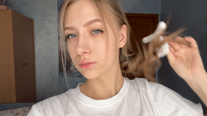 Woman styles hair with clip in Krasnoyarsk room