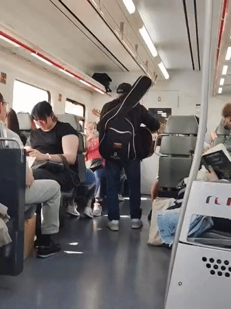 Street musician performs guitar aboard moving train in Mataró