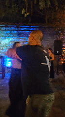 Outdoor dance event under colorful night lights with a DJ