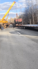 Crane loads dump truck onto flatbed in Russian town