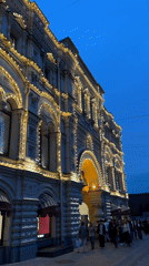 Evening scene captures Moscow pedestrians, pigeon near illuminated GUM store