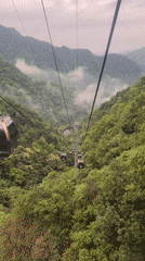 Cable cars ascend misty mountain toward temple in Wulingyuan