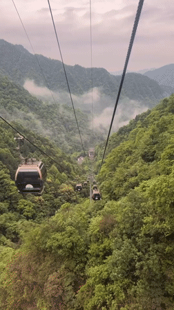Cable cars ascend misty mountain toward temple in Wulingyuan