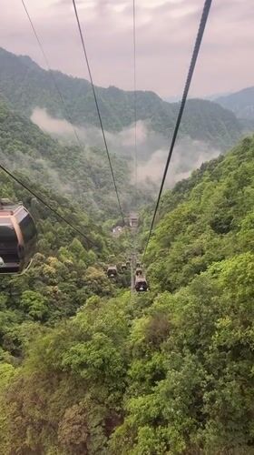 Cable cars ascend misty mountain toward temple in Wulingyuan