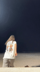 Person walks small dog on Montenegro beach at night