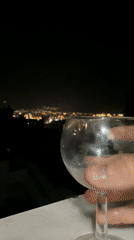 Wine glass photographed overlooking nighttime cityscape in Šušanj