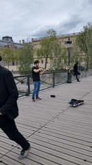 Street musician performs along Seine as Parisians enjoy riverside afternoon