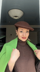 Woman displays green coat indoors in Krasnoyarsk