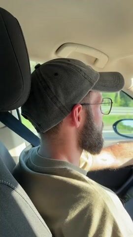 The video begins with a close-up of a man wearing a baseball cap and glasses, driving a car. The camera then pans to the dashboard, showing the steering wheel and a GPS screen. The car is on a highway, with trees and fields visible on either side. The video continues to show the road ahead, with other cars in the distance. The time displayed on the dashboard is 16:33. The car's speed is indicated as 93 km/h.