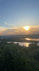 Woman documents sunset riverside moment with dog in Nizhny Novgorod
