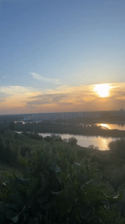 Woman documents sunset riverside moment with dog in Nizhny Novgorod