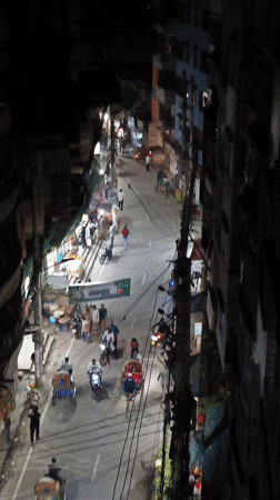 Nighttime street activity captured in busy Dhaka neighborhood