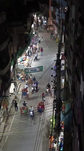 Nighttime street activity captured in busy Dhaka neighborhood